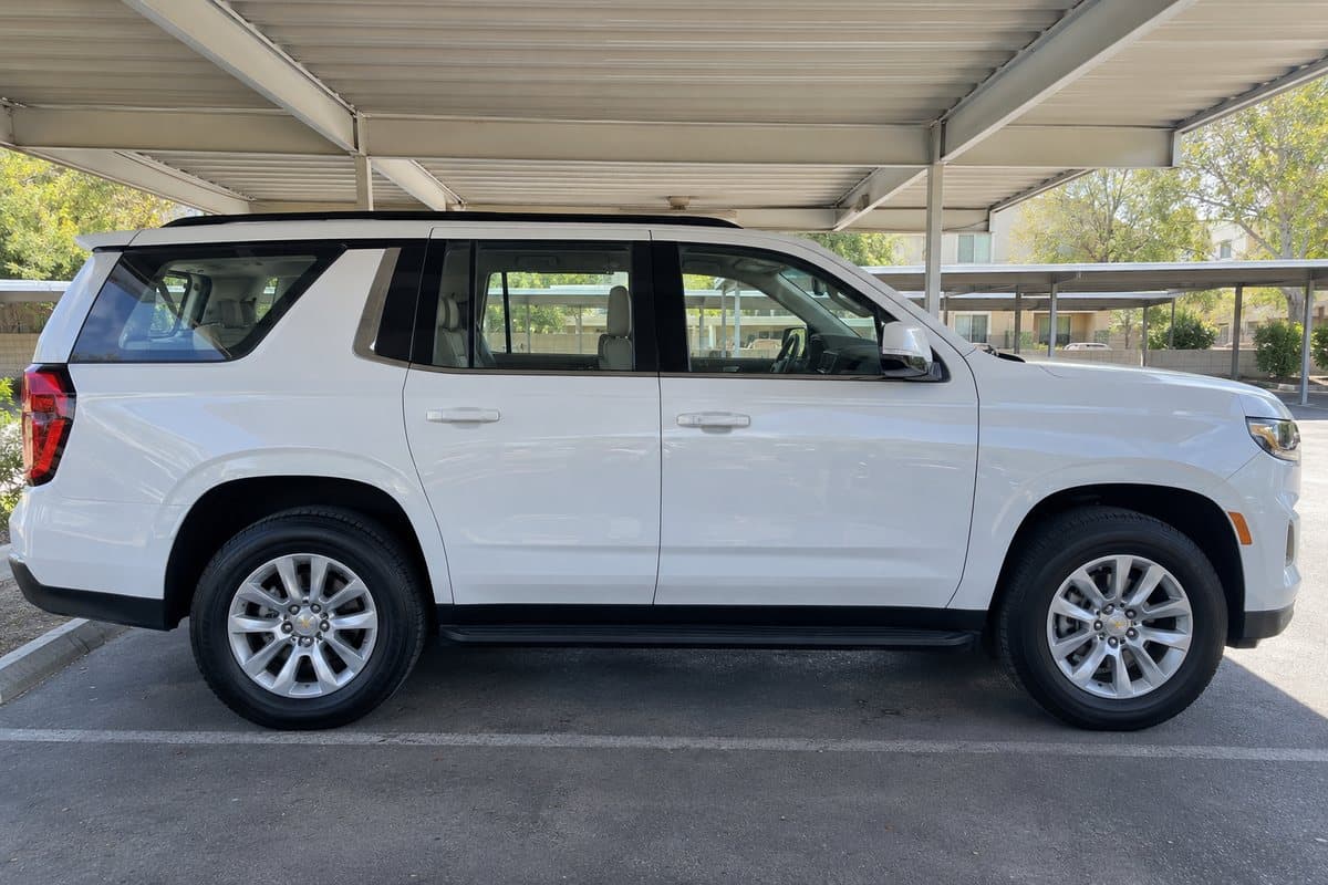 A white Chevy Tahoe under a covered carport, its windows half clear and half tinted