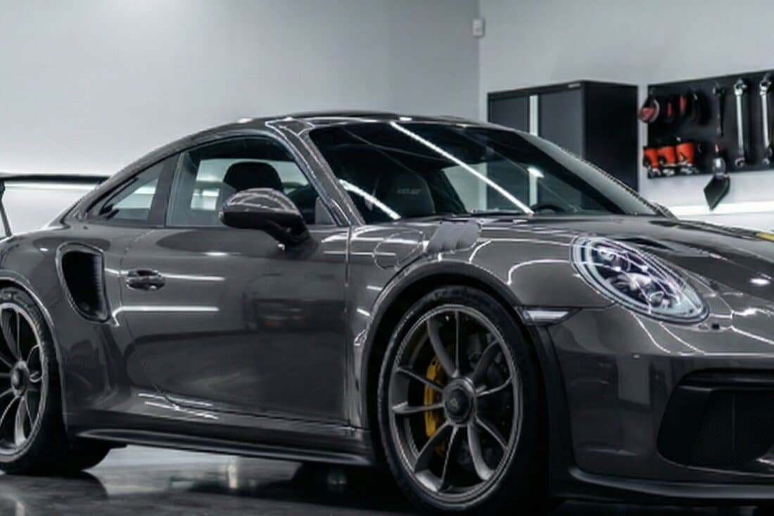 A grey sports car in a studio, its windows half clear and half tinted