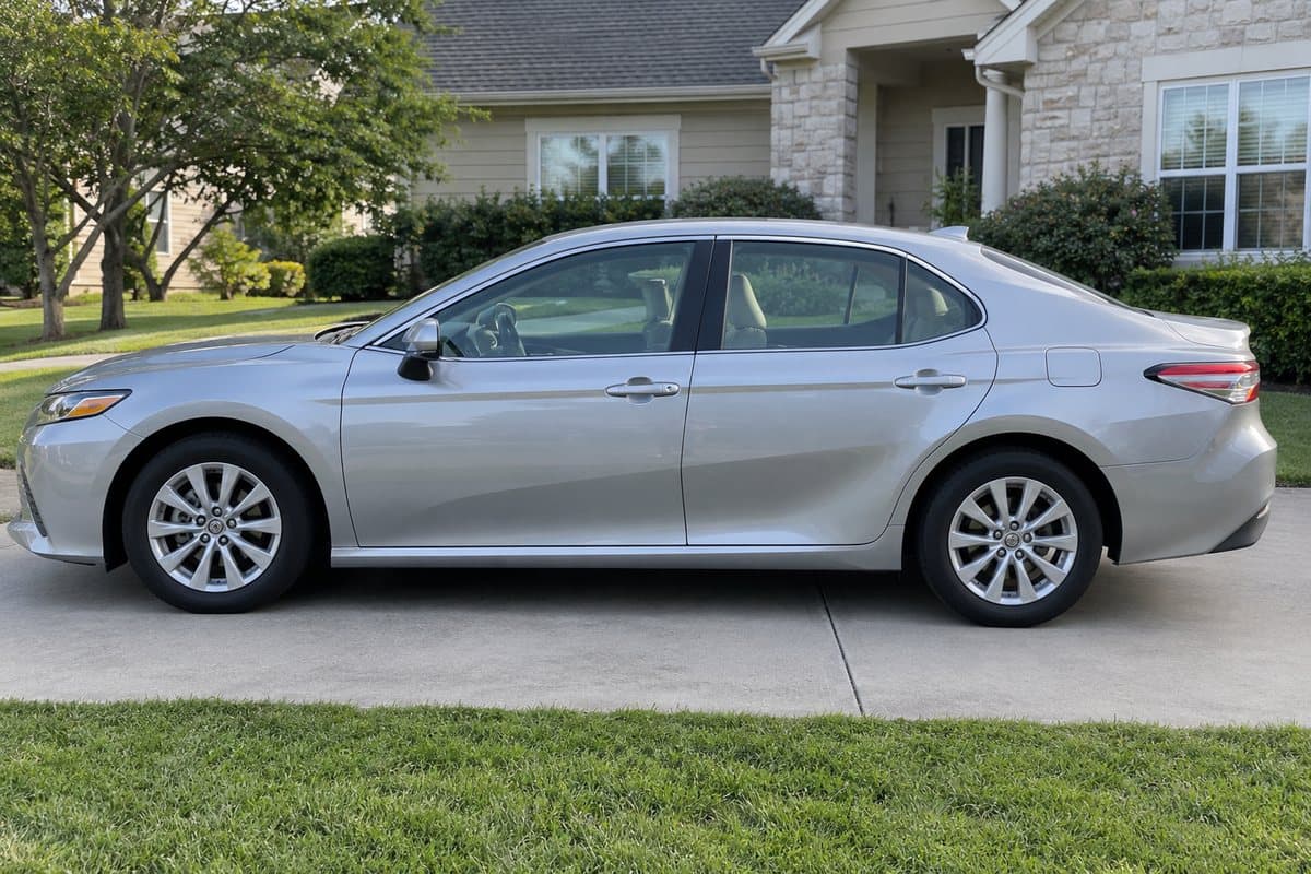 A silver Toyota Camry on a driveway, its windows half clear and half tinted