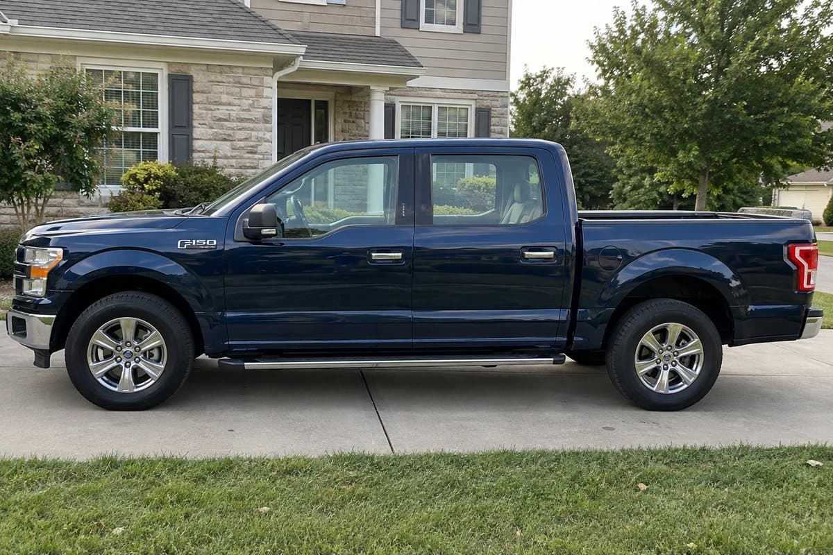 A dark blue metallic Ford F-150 on a driveway, its windows half clear and half tinted